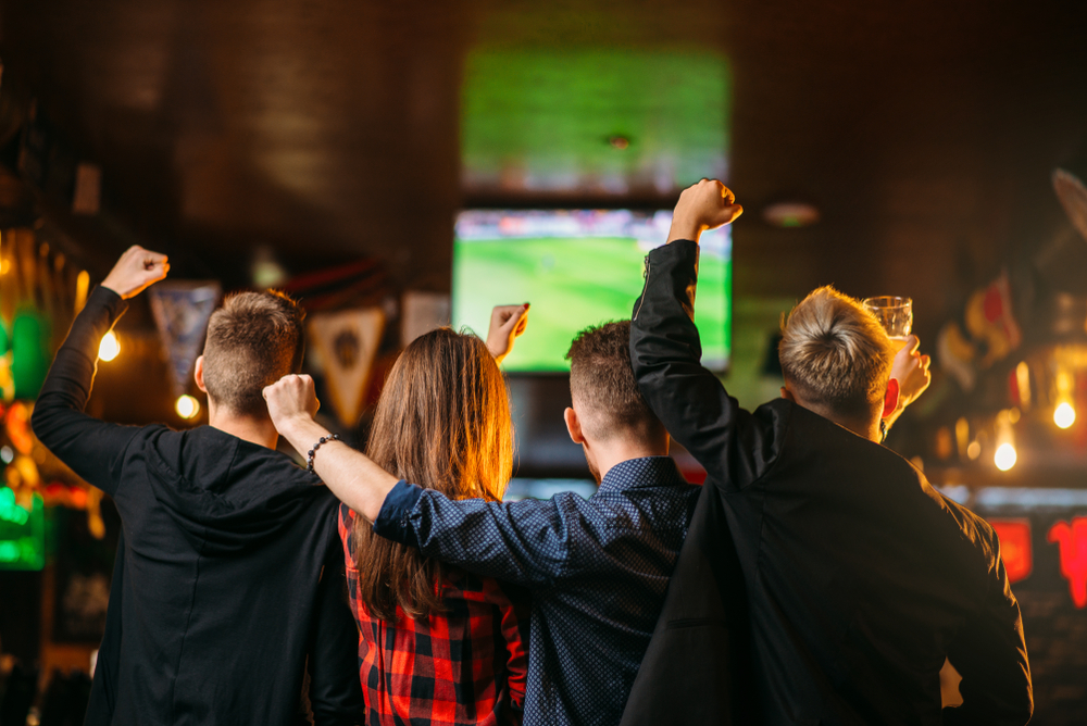 des gens regarent un programme sportif dans un bar
